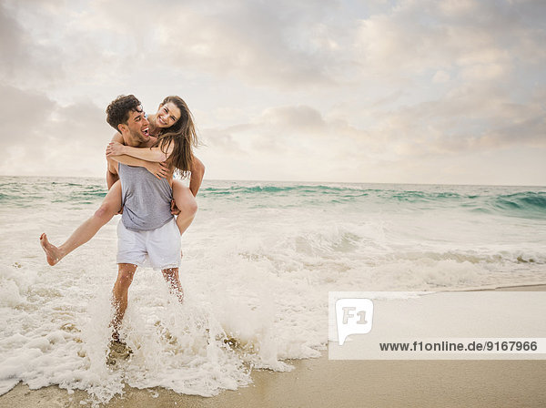 Caucasian couple playing on beach