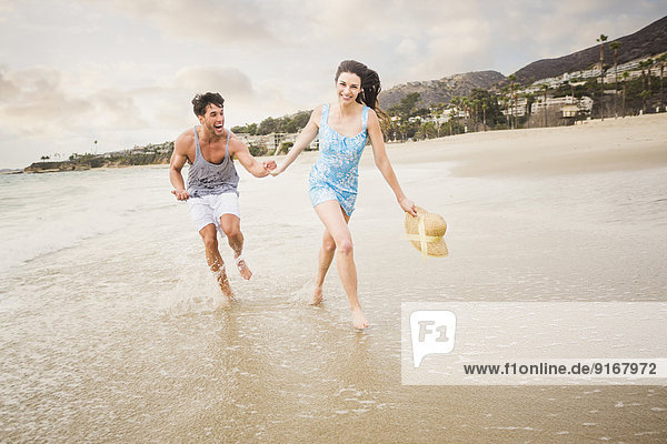 Caucasian couple running on beach