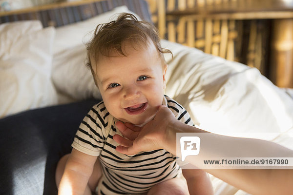 Caucasian baby laughing on bed