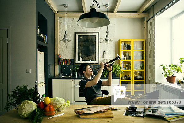 Caucasian man playing trumpet in kitchen