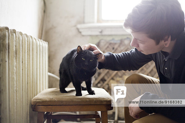Caucasian man petting cat in living room