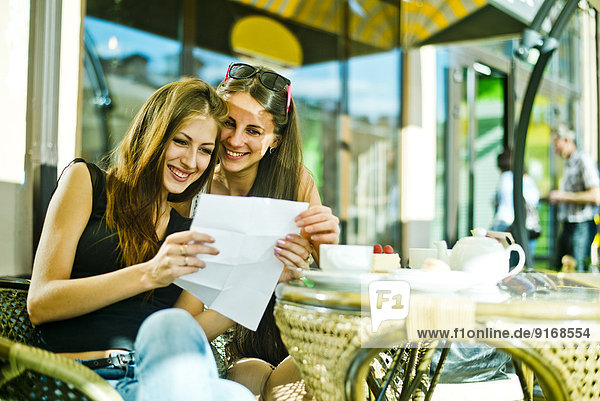 Women reading map together at sidewalk cafe