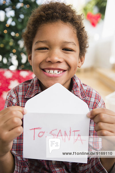 Black boy holding letter to Santa Claus
