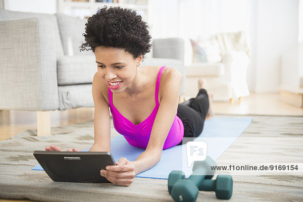 Black woman using digital tablet to work out