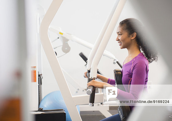 Mixed race woman using exercise machine in gym
