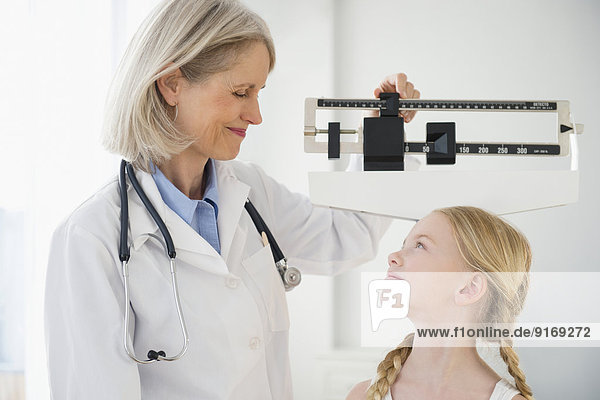 Caucasian doctor weighing patient