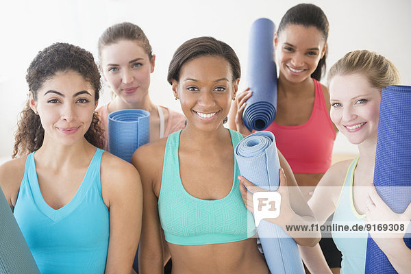 Women smiling together with exercise mats