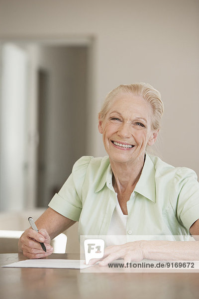 Senior Caucasian woman writing at table