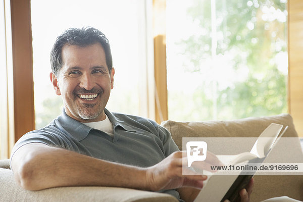 Hispanic man reading on sofa