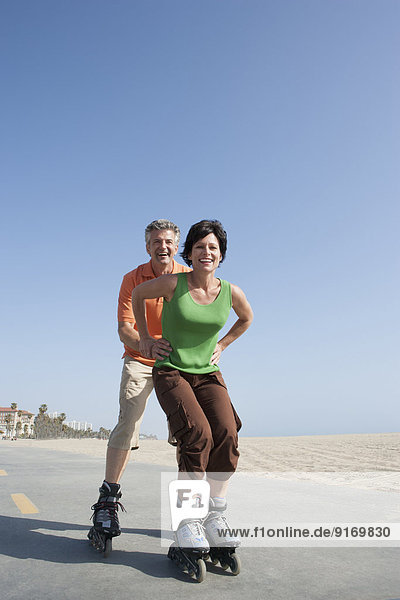 Caucasian couple rollerblading by beach