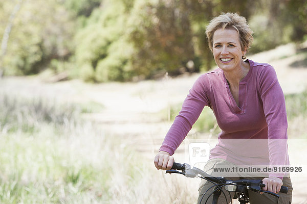 Senior Caucasian woman riding bicycle on rural path