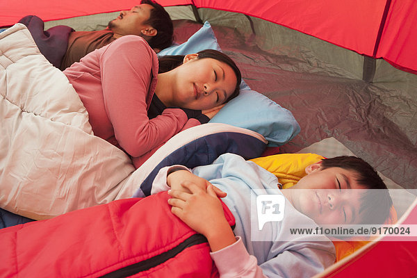 Asian family sleeping in tent
