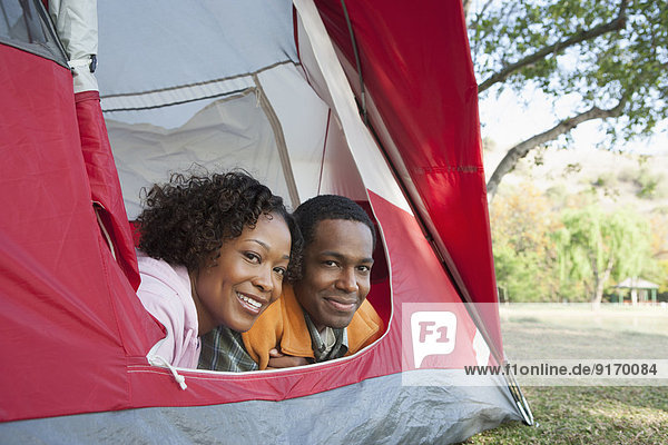 Couple peeking out of tent at campsite