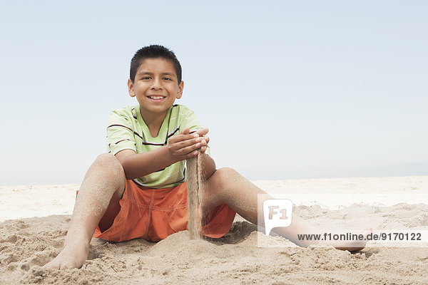 Hispanic boy playing in sand on beach