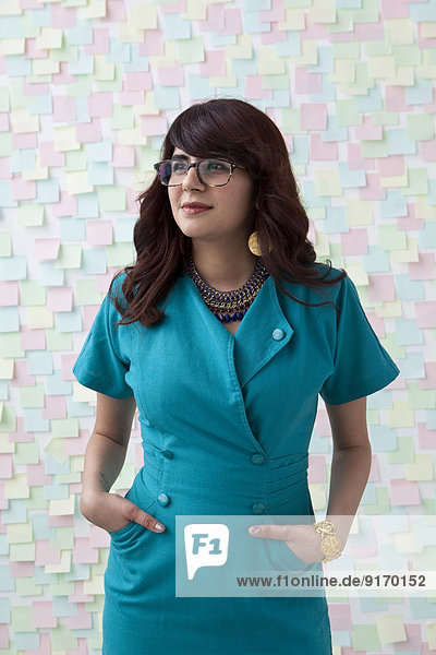 Mixed race businesswoman by wall of sticky notes