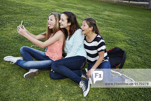 Teenage girls taking pictures in grass