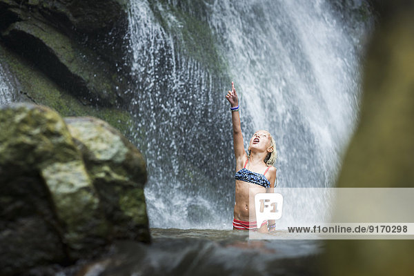 Caucasian girl playing in jungle waterfall