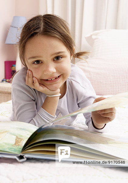 Mixed race girl reading on bed