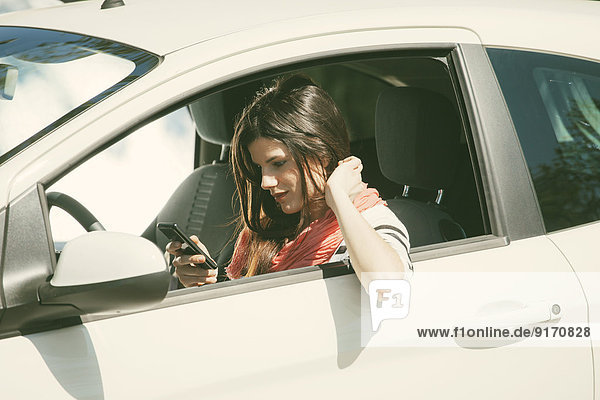 Spanien  Barcelona  Junge Frau mit Handy im Auto
