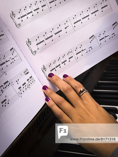 Junge Frau spielt Klavier mit Noten  Teilansicht