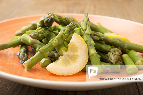 Green asparagus with slice of lemon on plate