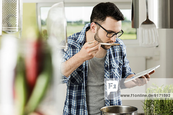 Junger Mann beim Kochen in der Küche zu Hause