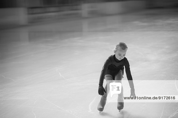 Young female figure skater moving on ice rink at competition