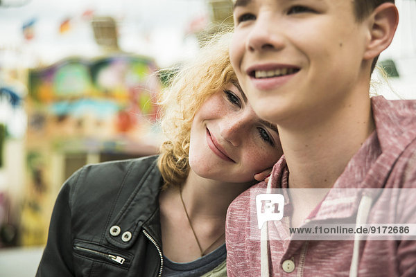 Portrait of happy teenage couple at fun fair