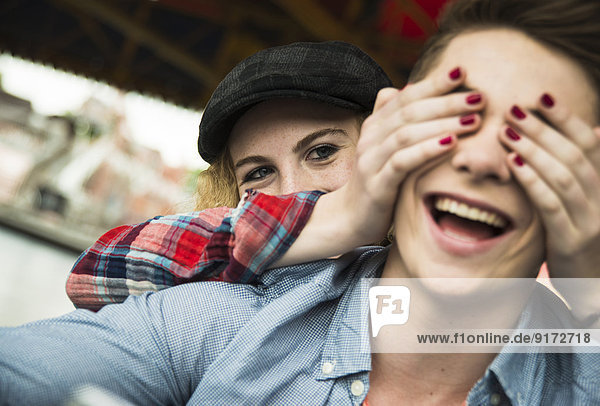 Teenage girl covering eyes of her boyfriend with her hands