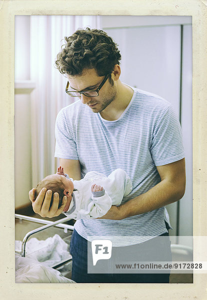 Vater hält sein Neugeborenes im Krankenhauszimmer fest