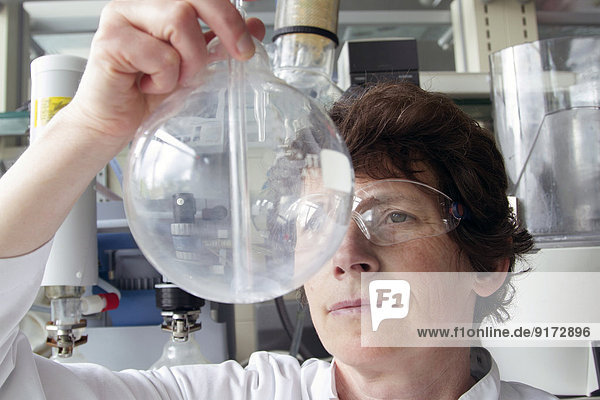 Chemikerin beim Blick auf Rundkolben im Labor