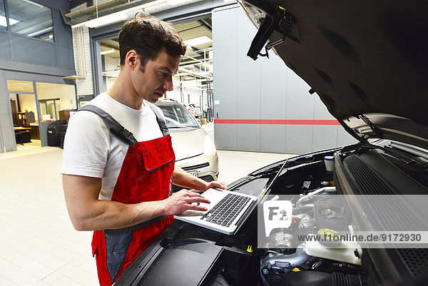 Car mechanic in a workshop using modern diagnostic equipment