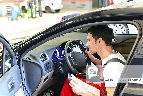Car mechanic sitting in car with clipboard