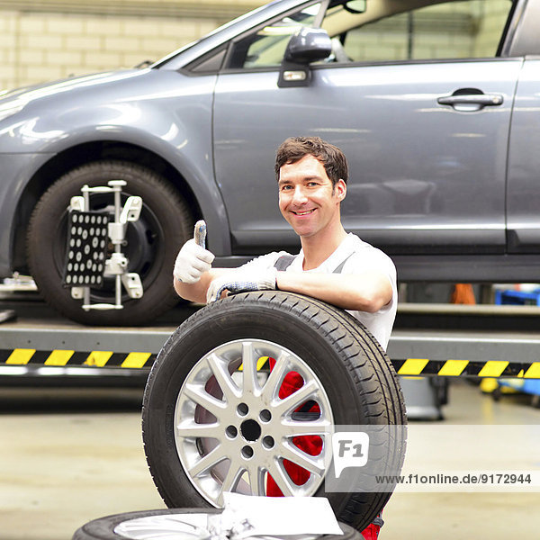 Porträt eines selbstbewussten Kfz-Mechanikers in einer Reifenwerkstatt