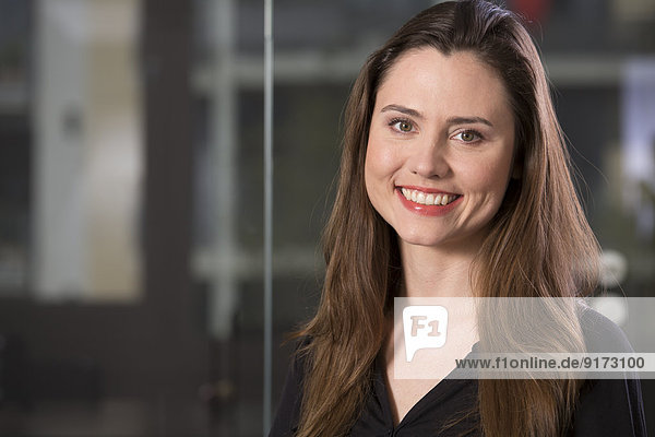 Porträt der lächelnden Geschäftsfrau vor der Glasscheibe