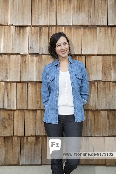Porträt einer jungen kreativen Geschäftsfrau vor Holzschindelverkleidung