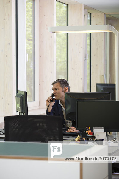 Portrait of business man telephoning at workplace