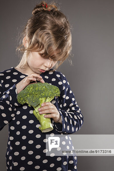 Portrait of little girl examining a broccoli