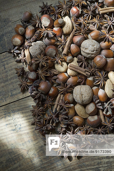 Star anise walnuts hazelnuts almonds and cinnamon sticks on wood partial view