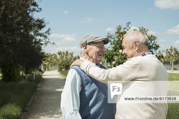 Zwei fröhliche alte Männer stehen sich gegenüber im Park.