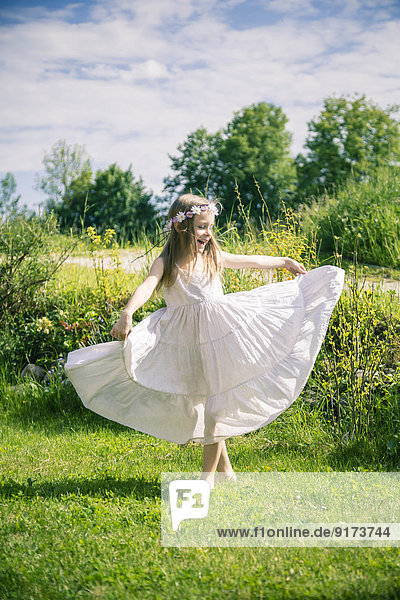 Mädchen in weißem Sommerkleid auf der Wiese