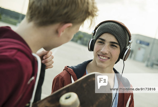 Two boys with headphones and skateboard