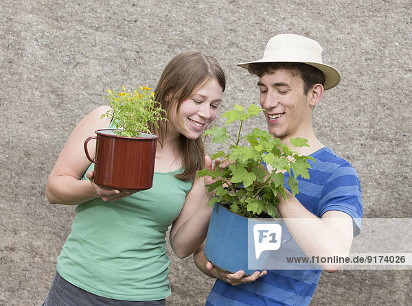 Junges Paar mit zwei Topfpflanzen  Tagetes tenuifolia und Ribes