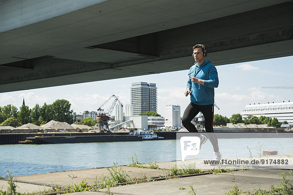 Man with headphones jogging at riverside
