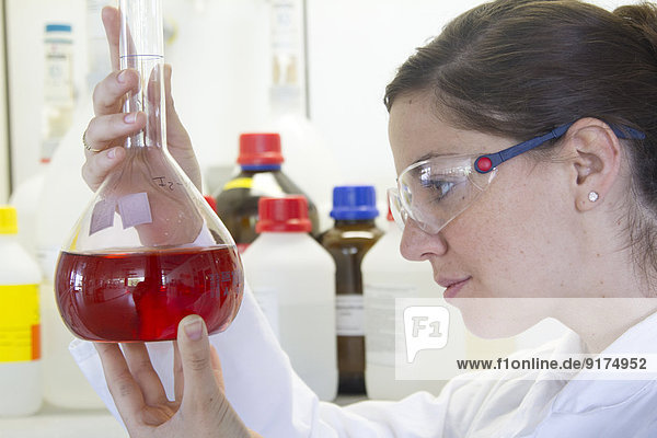 Porträt einer Chemikerin mit Erlenmeyerkolben mit roter Flüssigkeit