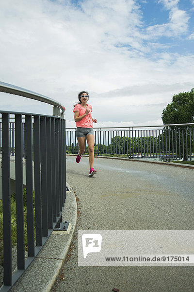 Junge Frau beim Joggen auf einer Brücke