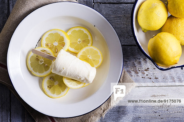 Schale mit Zitronen und Teller mit hausgemachtem Zitronencremeeis auf Zitronenscheiben  erhöhte Ansicht