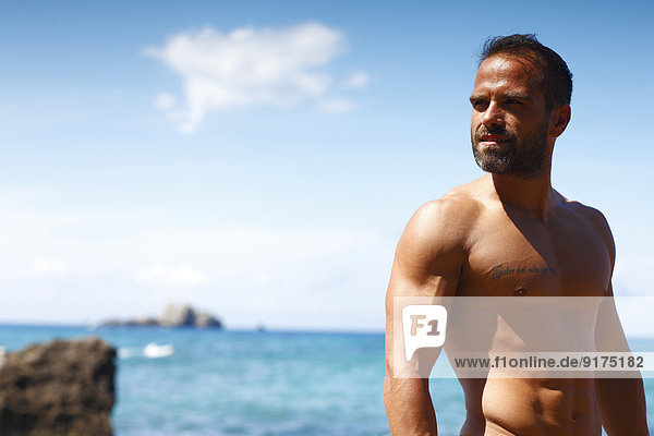 Griechenland,  Ionische Inseln,  Korfu,  Mann ohne Hemd,  der das Sonnenlicht vor dem Meer genießt