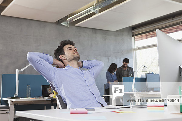 Porträt eines Mannes  der sich an seinem Arbeitsplatz im Büro entspannen kann.