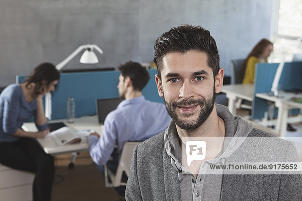 Porträt eines lächelnden Mannes in einem Großraumbüro